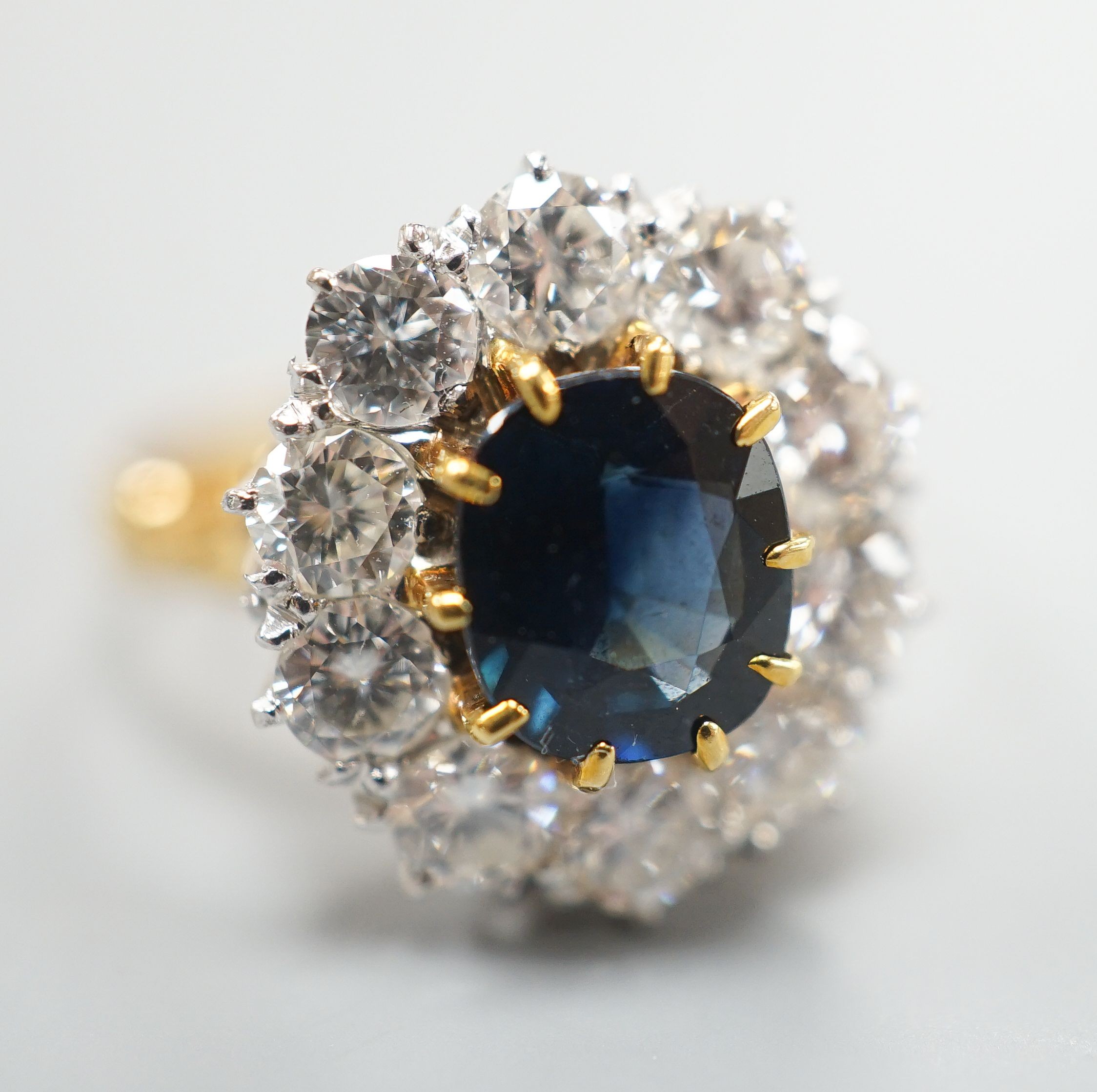 A modern 18ct gold, sapphire and diamond set oval cluster ring, size P/Q, gross weight 6.2 grams.